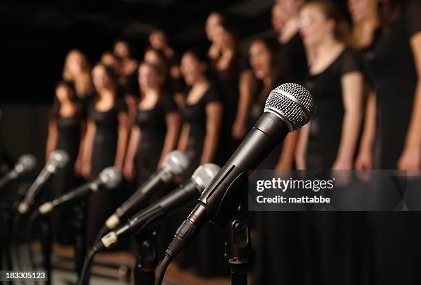shot of microphones with choir in the background - choir stock pictures, royalty-free photos & images