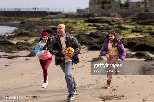 chasing after dad on a beach - family at beach stock pictures, royalty-free photos & images