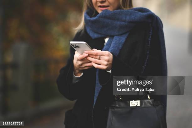 close up of a woman's hands using mobile phone outoors. - casaco azul imagens e fotografias de stock