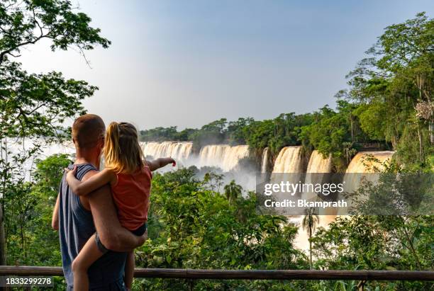 padre e hija disfrutando de las impresionantes y poderosas cataratas del iguazú en el parque nacional iguazú en la frontera de argentina y brasil, américa del sur - garganta del diablo fotografías e imágenes de stock