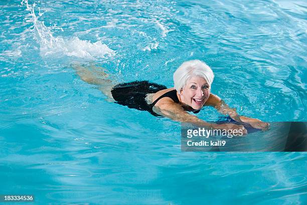 active senior woman exercising in swimming pool - senior kicking stock pictures, royalty-free photos & images