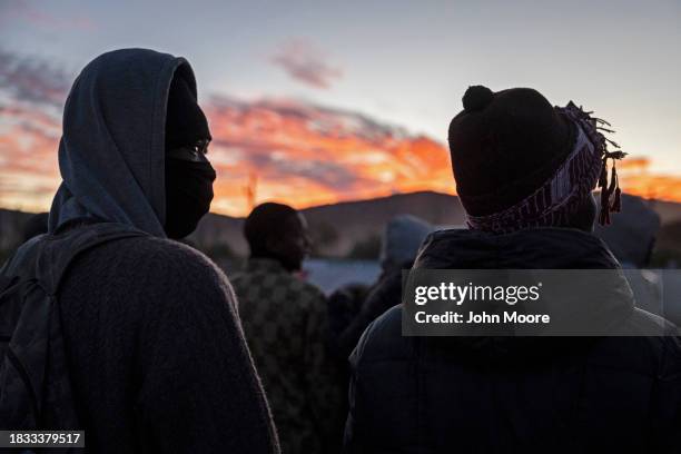 Immigrants from Mauritania wait to be processed by U.S. Border authorities after spending the night in the desert on December 05, 2023 in Lukeville,...