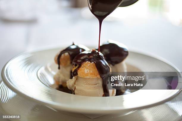 closeup picture of profiteroles bathing in chocolate - eclair stockfoto's en -beelden