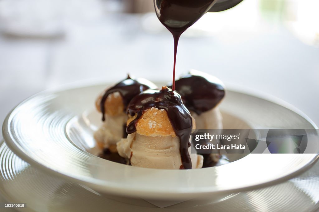 Closeup picture of profiteroles bathing in chocolate