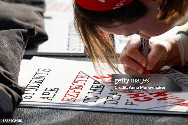 An activist writes on a sign during a Title IX rally at Lafayette Park near the White House on December 05, 2023 in Washington, DC. Activists and...