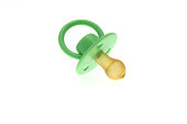 High key image of an infants green dummy or pacifier