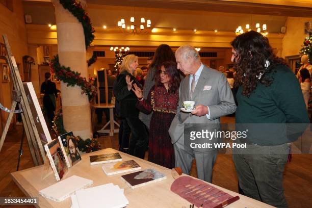 King Charles III is shown a series of paintings during a festive themed 'Celebration of Craft' at Highgrove House on December 8, 2023 in Tetbury,...