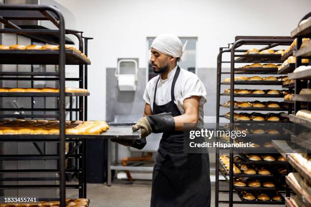 baker taking trays of bread out of the oven at an industrial bakery - chefs whites stock pictures, royalty-free photos & images
