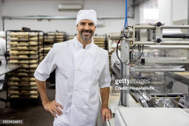 happy baker working at an industrial bakery - voedsel-verwerkingsbedrijf stockfoto's en -beelden