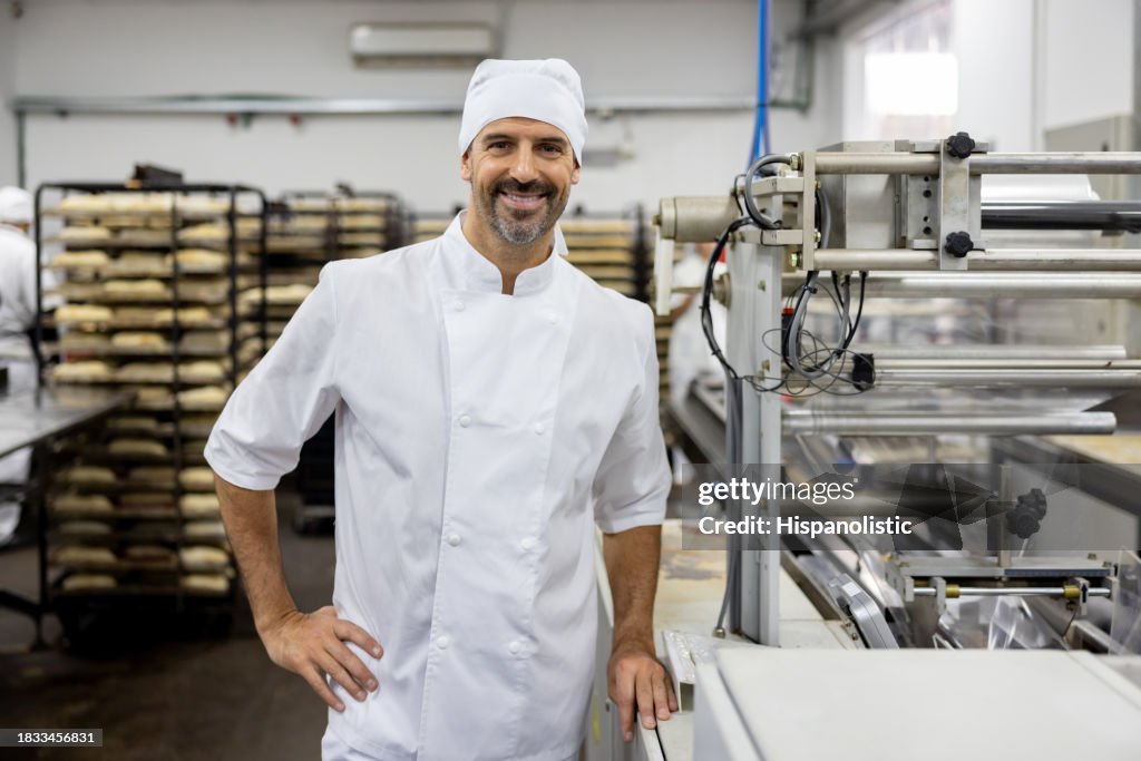Happy baker working at an industrial bakery