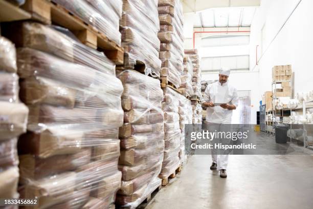 worker taking inventory of the flour at an industrial bakery - flour bag stockfoto's en -beelden