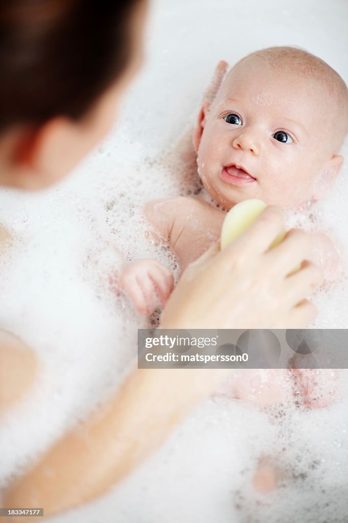 Newborn baby having a bath with mother