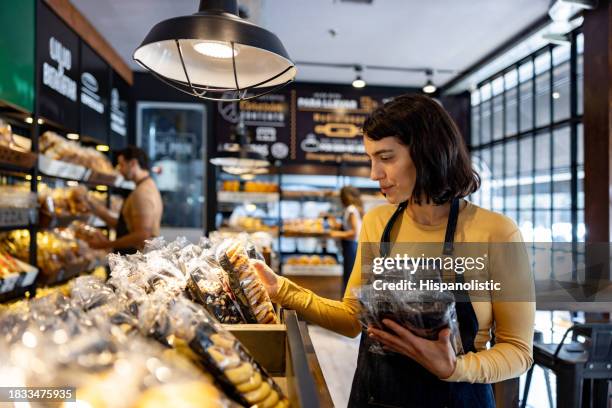 retail clerk working at a bakery and restocking the shelves - bakery shelves stock pictures, royalty-free photos & images