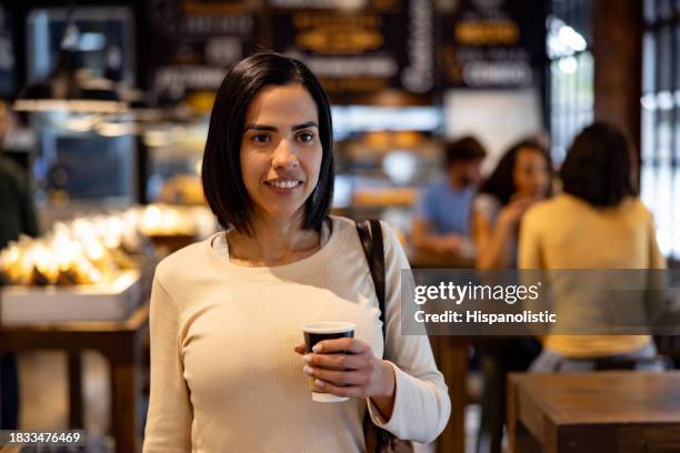 happy woman buying a cup of coffee on the go at a cafe - leaving restaurant stock pictures, royalty-free photos & images