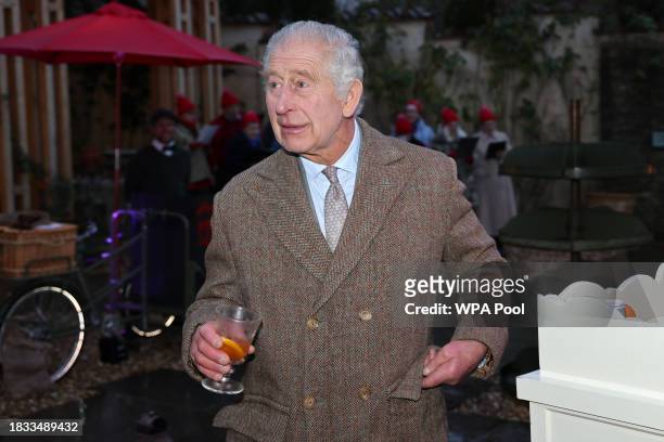 King Charles III tries a glass of mulled cider during a festive themed 'Celebration of Craft' at Highgrove House on December 8, 2023 in Tetbury,...