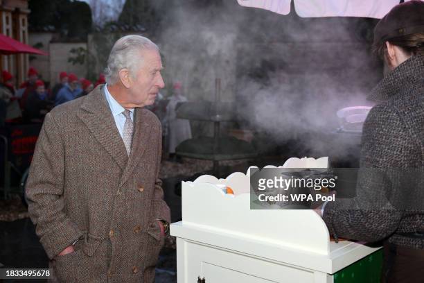 King Charles III waits to be given a glass of mulled cider to taste during a festive themed 'Celebration of Craft' at Highgrove House on December 8,...