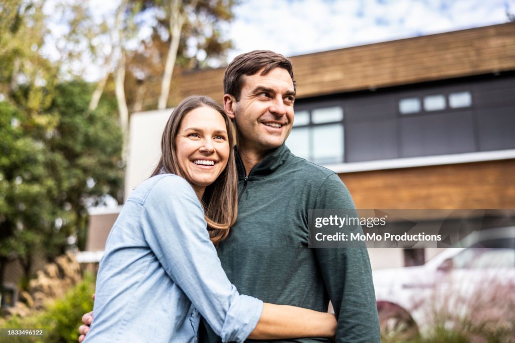 Portrait of married couple in front of modern home