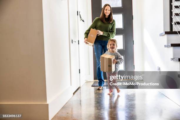 toddler girl bringing delivery package into home - online shopping stock pictures, royalty-free photos & images