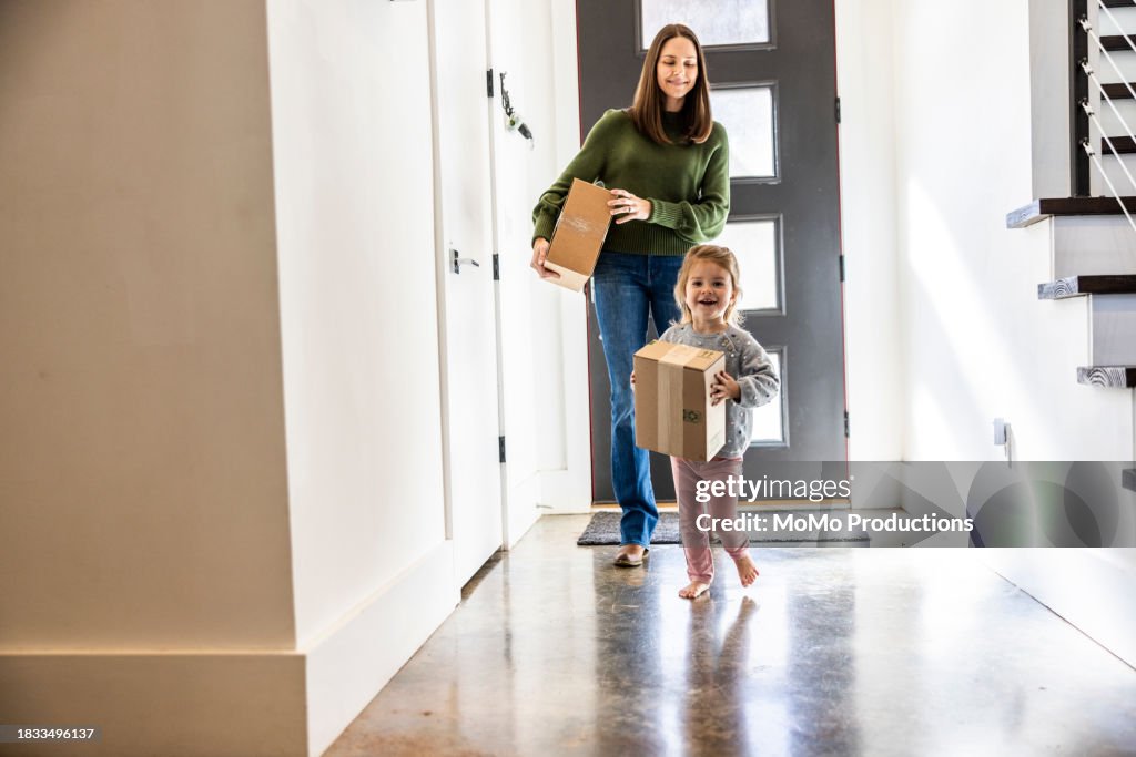 Toddler girl bringing delivery package into home