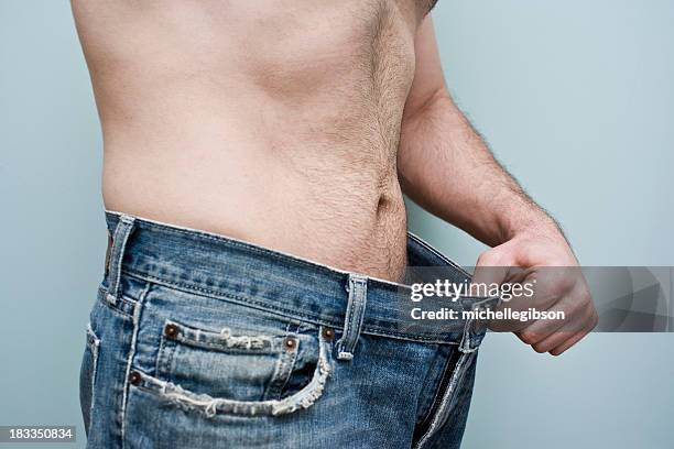 man showing weight loss by showing his loose pants - male stomach stock pictures, royalty-free photos & images