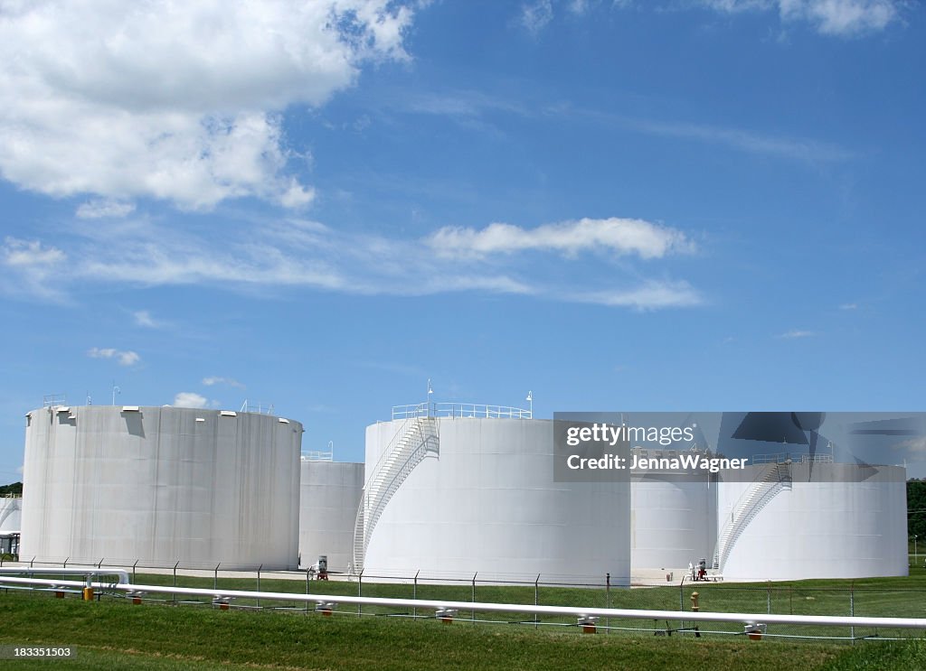 Several white storage tanks in a grassy field