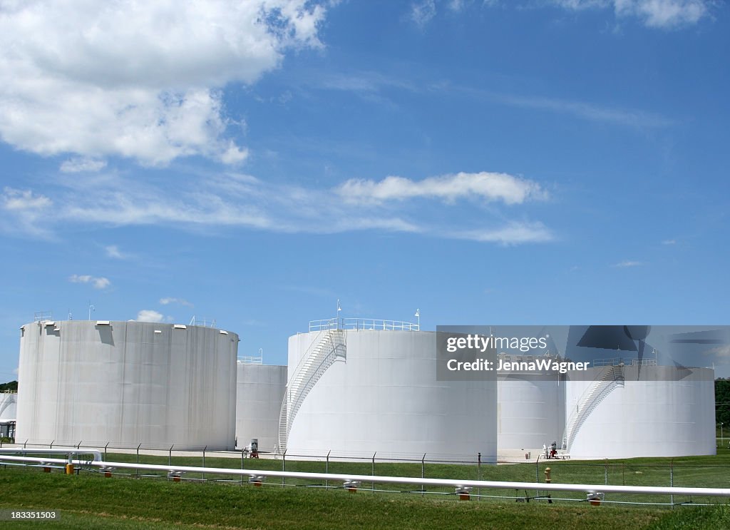 Several white storage tanks in a grassy field