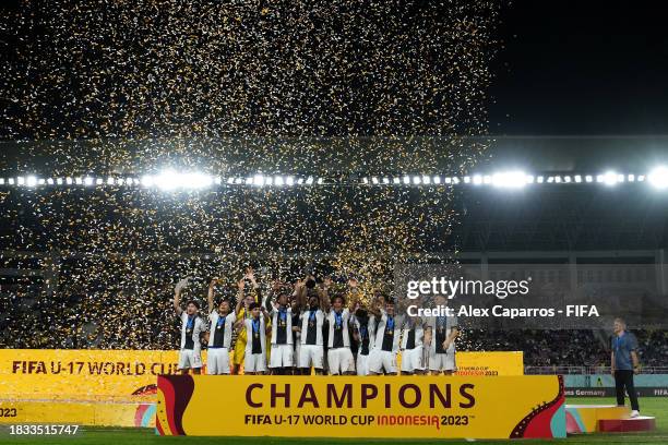 Germany players lift the FIFA U-17 World Cup winners trophy as Head Coach Christian Wueck looks from the distance following victory in the FIFA U-17...