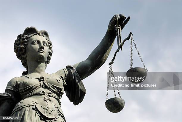 statue of a woman holding a balance scale - gerechtigheid stockfoto's en -beelden
