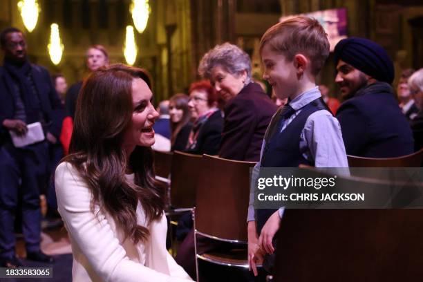 Britain's Catherine, Princess of Wales speaks with a young guest at the "Together At Christmas" Carol Service" at Westminster Abbey in London on...