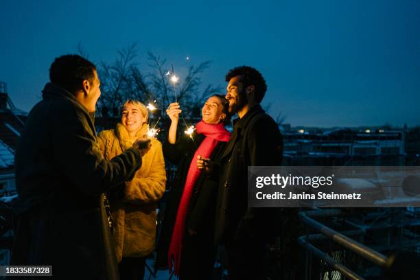 shot of a cheerful group of friends standing on a terrace at night with sparklers in hand - silvester berlin stock-fotos und bilder