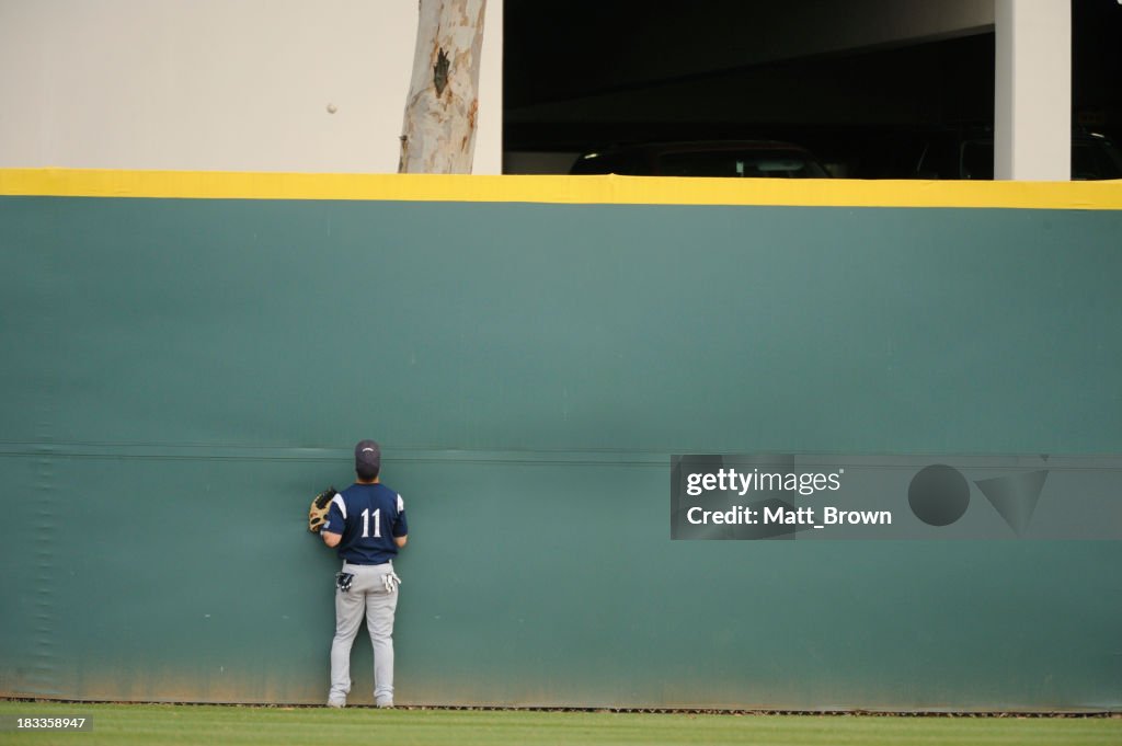 A baseball player searching desperately for his ball