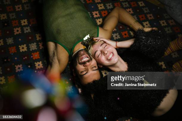a couple is lying on the floor, laughing on new year's eve - bottle champagne from above stock-fotos und bilder