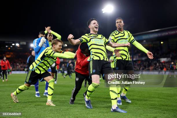 Declan Rice of Arsenal is pushed in front of fans of Arsenal as he celebrates with teammates after defeating Luton Town during the Premier League...