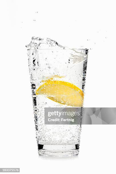 lemon slice splashing into soda water - koolzuurhoudend water stockfoto's en -beelden