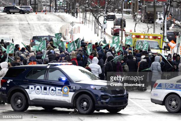 An ambulance navigates a safety corridor as public sector workers and supporters strike outside the Centre hospitalier de l'Universite de Montreal...