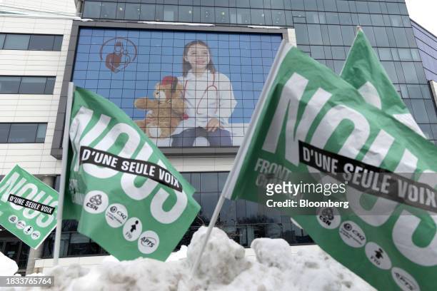 Flags stuck in a snowbank as public sector workers and supporters strike outside McGill University Health Centre in Montreal, Quebec, Canada, on...