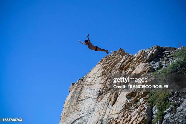 Cliff diver of La Quebrada performs after resuming activities following the passage of Hurricane Otis in Acapulco, Guerrero state, Mexico on December...