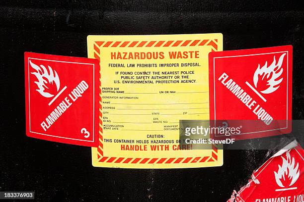 hazardous waste lables on a barrel of chemicals - brandbaar stockfoto's en -beelden