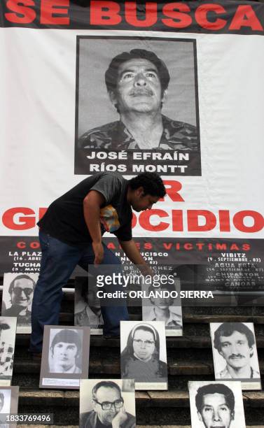 Human rights activist places the pictures of victims of the Guatemalan civil war in front of a request poster of former dictator Efrain Rios Montt,...