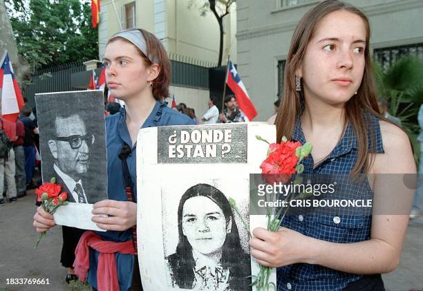 Sympathizers of the Communist Party stand with flowers and portraits of former Chilean ruler Salvador Allende and a citizen who disappeared 23...
