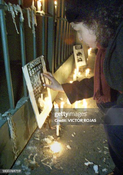 Woman touches in Santiago 08 August 2000 the poster of someone who disappeared in the coup that propelled Chilean dictator Augusto Pinochet to power...