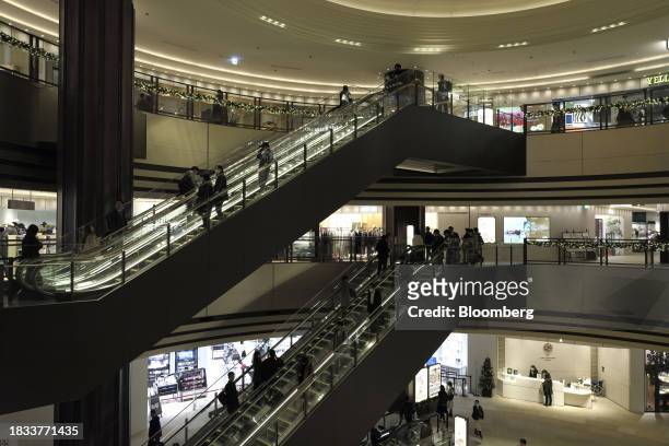 Shoppers ride escalators inside the Tokyo Midtown Hibiya in the Yurakucho area of Tokyo, Japan, on Friday, Japan, on Dec. 8, 2023. Inflation data are...