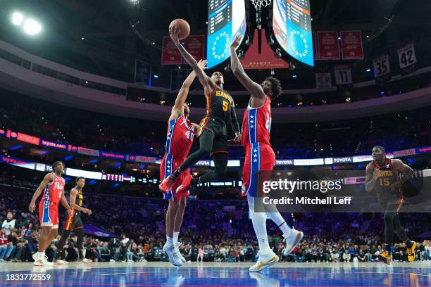 Dejounte Murray of the Atlanta Hawks shoots the ball against Nicolas Batum and Joel Embiid of the Philadelphia 76ers in the first quarter at the...