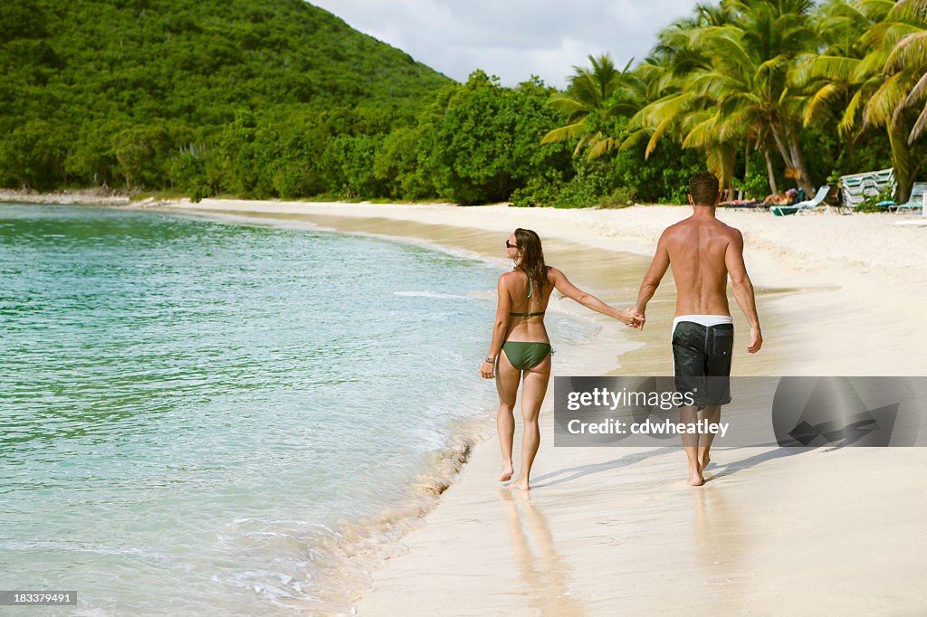 Honeymoon couple holding hands and walking along a Caribbean beach