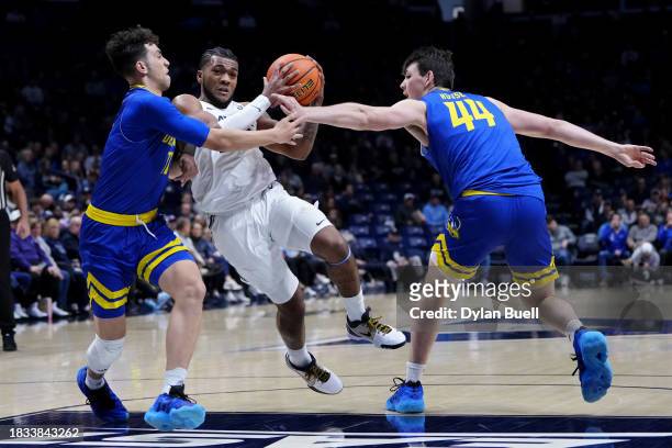 Dayvion McKnight of the Xavier Musketeers dribbles the ball while being guarded by Kobe Jerome and Tyler Houser of the Delaware Blue Hens in the...