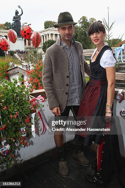 Pep Guardiola, head coach of Bayern Muenchen poses with his wife Cristina Serra in front of the ensemble of the Bavaria statue, a monumental bronze...