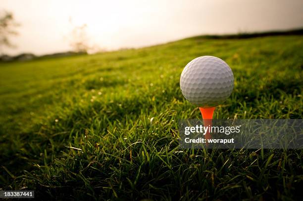 golf ball on an orange tee in the grass - teeing off stock pictures, royalty-free photos & images
