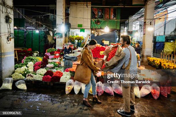 wide shot woman admiring large bouquets of roses held by friend - same person different looks stock pictures, royalty-free photos & images