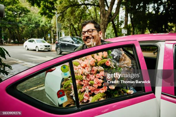 medium wide shot of man holding roses stepping out of taxi in city - man holding out flowers stock pictures, royalty-free photos & images