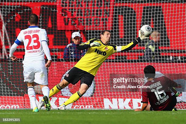 Rafael van der Vaart of Hamburg scores his team's first goal against goalkeeper Raphael Schaefer and Makoto Hasebe of Nuernberg during the Bundesliga...